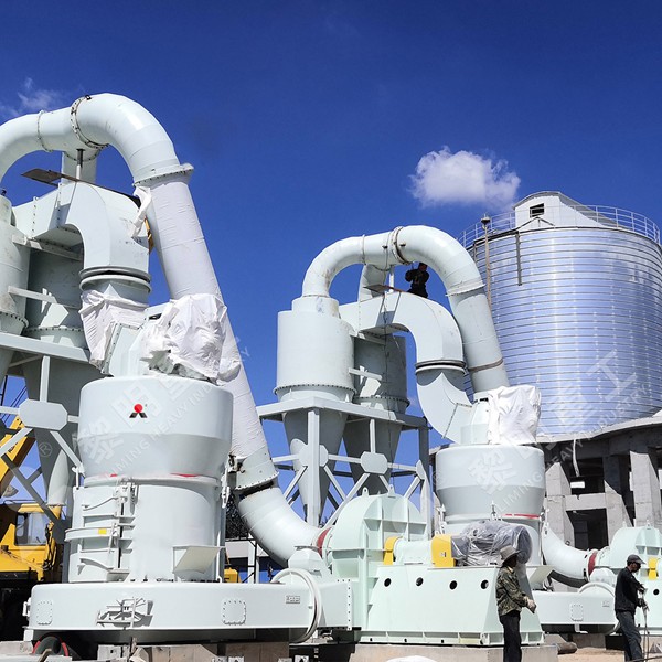 A Raymond Mill grinding unit installed within a modern industrial plant, showing the main mill body, cyclone separator, and connecting ductwork.